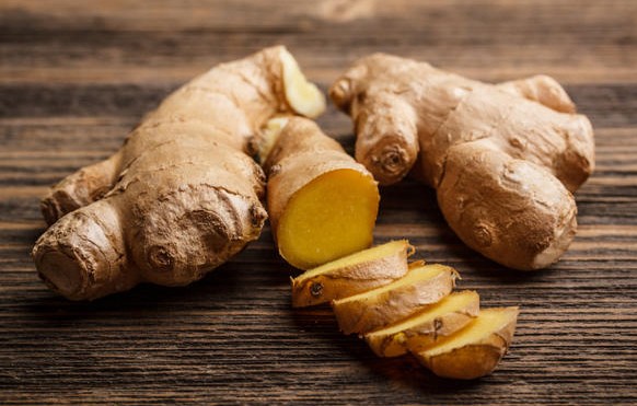 Fresh ginger, whole and sliced on rustic wooden корень имбиря